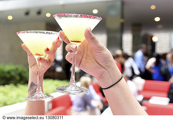 Cropped hands of female friends toasting martini glasses at restaurant