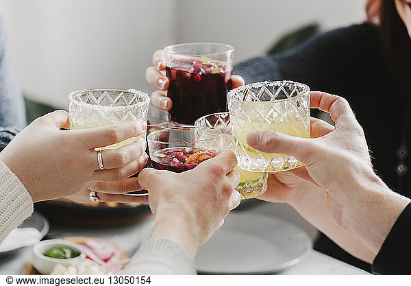 Cropped hands of friends toasting drinks in party at home