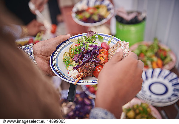 Cropped hands of woman holding meal in plate during social gathering on terrace
