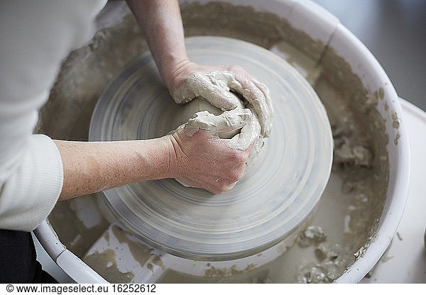 Cropped hands of woman molding pot in pottery class