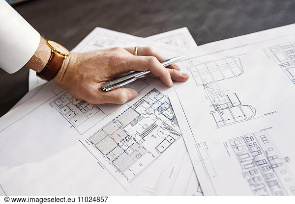 Cropped image architect working on blueprint at table in office
