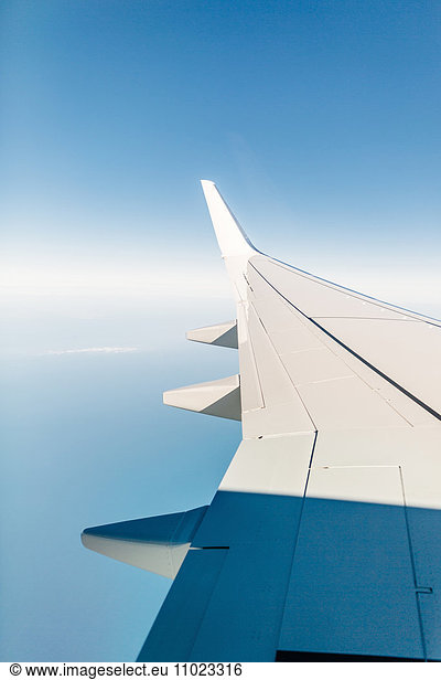 Cropped image of airplane wing against blue sky
