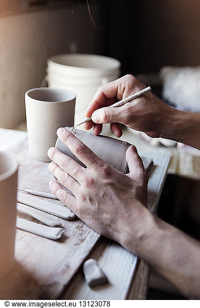 Cropped image of artist carving mug at workshop