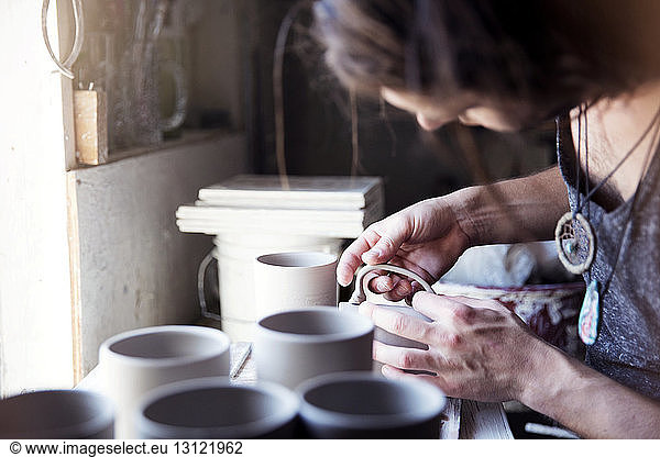 Cropped image of artist checking mug at workshop
