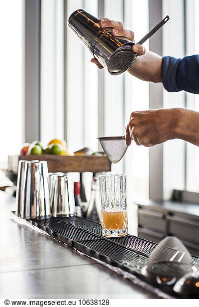 Cropped image of bartender making cocktail at bar