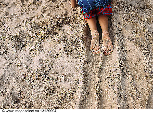 Cropped image of boy crawling in sand