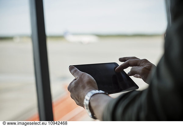 Cropped image of businessman using digital tablet at airport