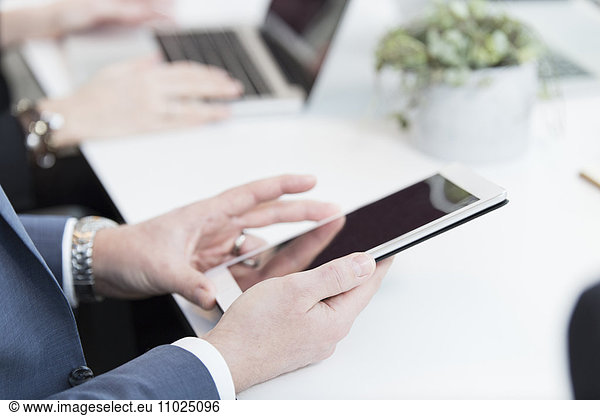Cropped image of businessman using digital tablet in meeting