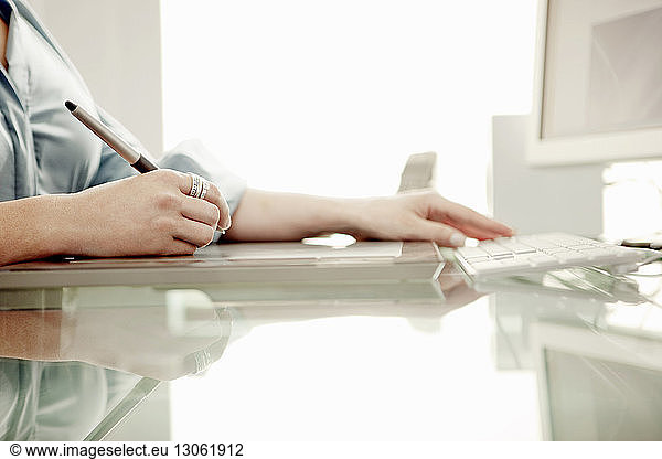 Cropped image of businesswoman using digital pen on table at office