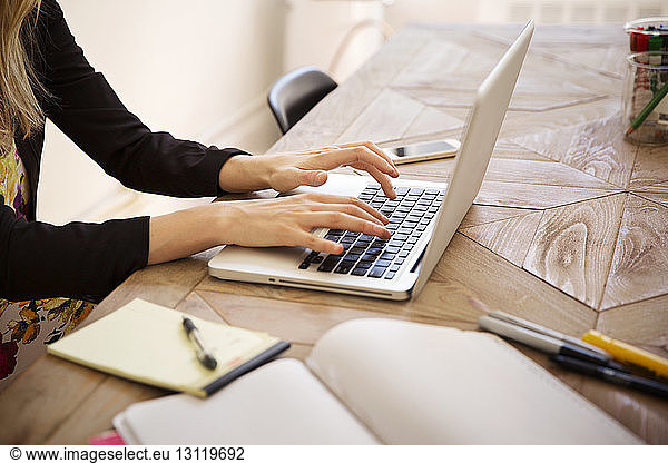 Cropped image of businesswoman using laptop at desk in office