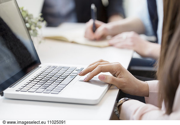 Cropped image of businesswoman using laptop at table in meeting