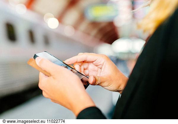 Cropped image of businesswoman using smart phone at railroad station