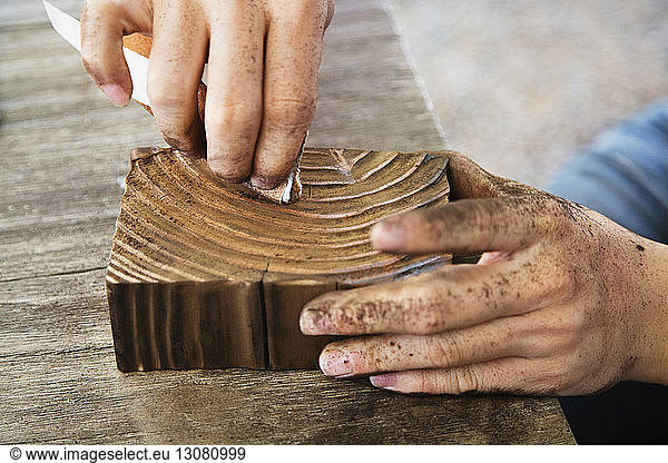 Cropped image of carpenter carving wood in workshop