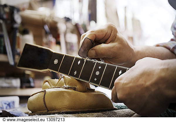 Cropped image of carpenter shaping guitar in workshop