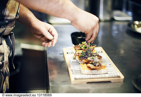 Cropped image of chef garnishing food at kitchen counter