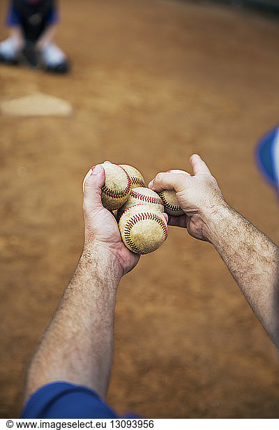 Cropped image of coach holding baseballs on field