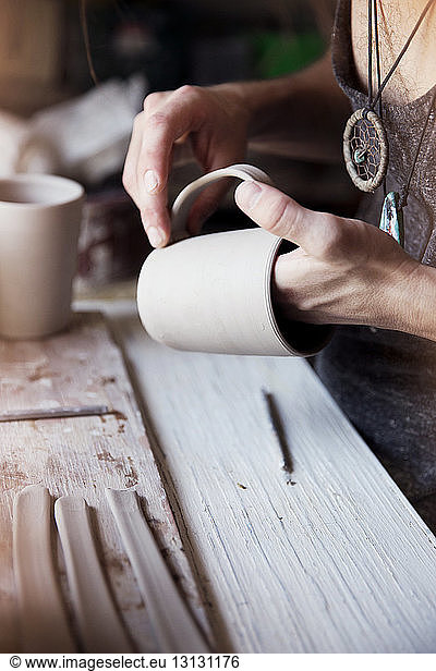 Cropped image of craftsman examining mug at workshop