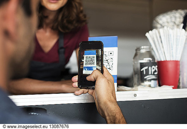 Cropped image of customer paying through smart phone at food truck