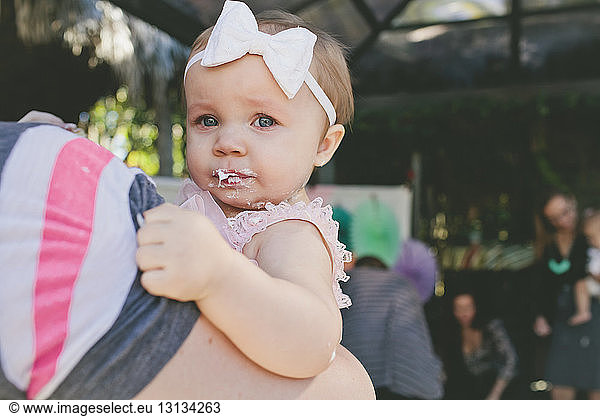 Cropped image of father carrying daughter at birthday party