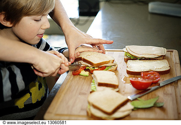 Cropped image of father making sandwich with son in kitchen