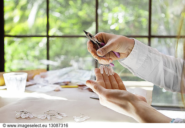 Cropped image of female artist making earrings at desk