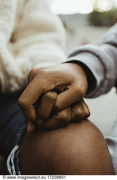 Cropped image of female teenager friends holding hands outdoors