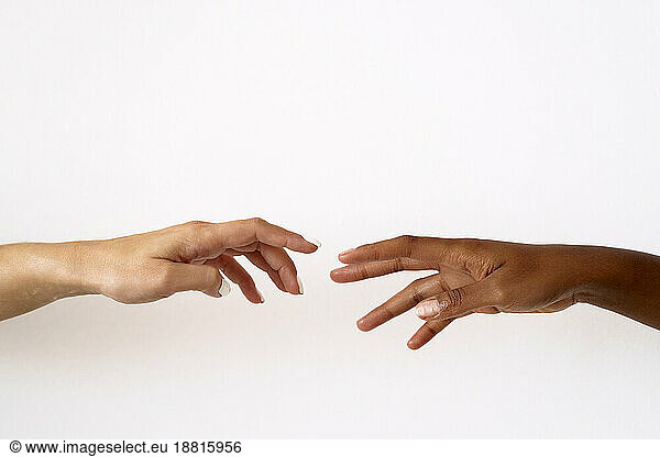 Cropped image of friends reaching to each other against white background