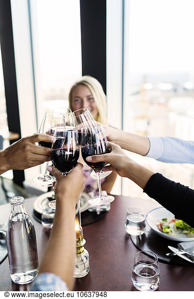 Cropped image of friends toasting with red wine in restaurant