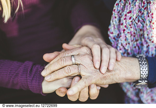 Cropped image of granddaughter and grandmother holding hands