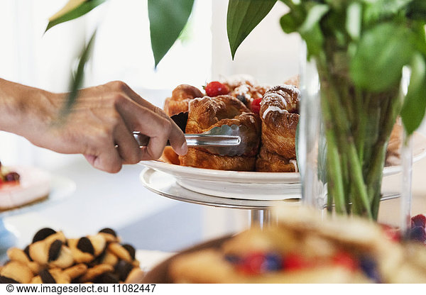 Cropped image of hand arranging desert on cakestand at cafe