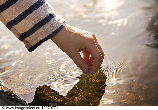 Cropped image of hand touching water