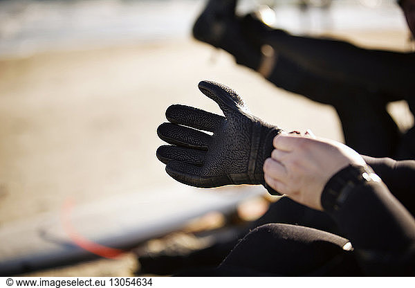 Cropped image of hand wearing sports glove at beach