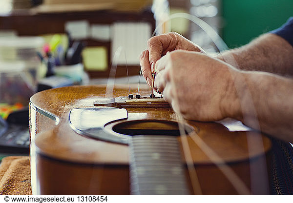 Cropped image of hands fixing strings on guitar