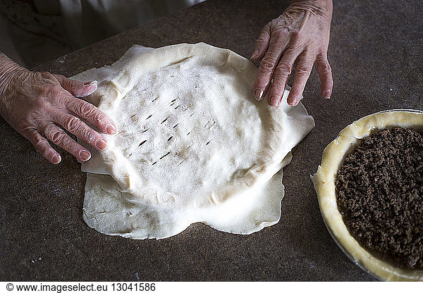 Cropped image of hands making meat pie at home