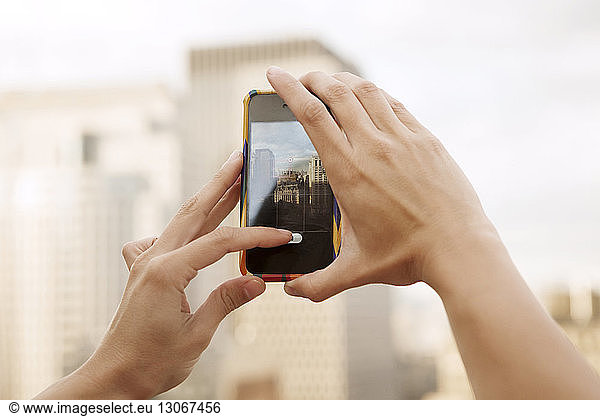Cropped image of hands photographing buildings