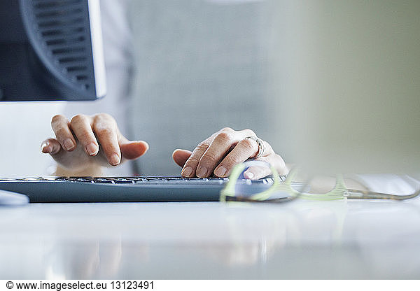 Cropped image of hands using computer keyboard at office desk