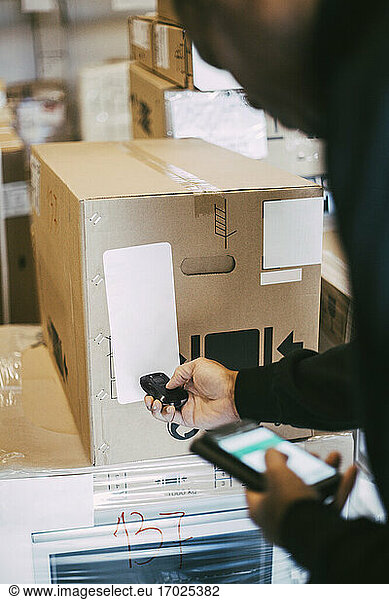 Cropped image of male worker scanning cardboard box with bar code reader at distribution warehouse