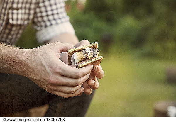 Cropped image of man holding smores at summer camp
