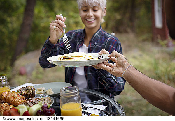 Cropped image of man offering pancakes to young woman during breakfast