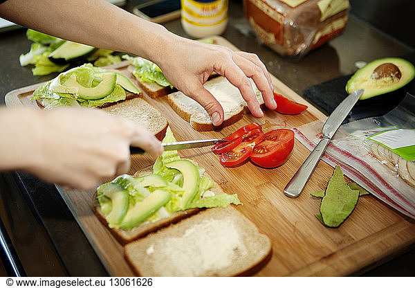 Cropped image of man preparing sandwich in kitchen