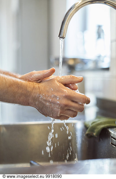 Cropped image of man washing hands in kitchen sink