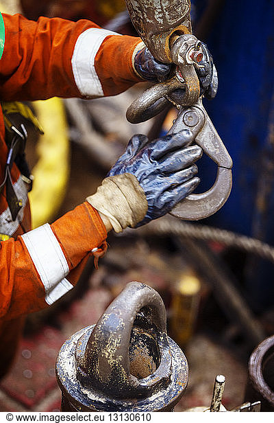 Cropped image of manual worker holding metallic hook