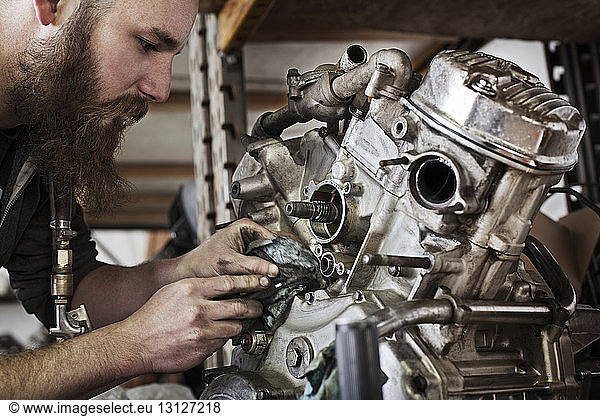 Cropped image of mechanic working on motorcycle engine at shop