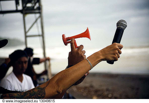 Cropped image of people holding microphone and siren