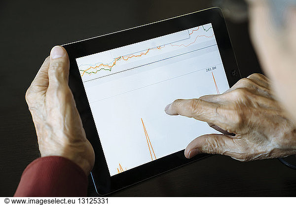 Cropped image of senior man analyzing graph on tablet computer in financial advisor's office