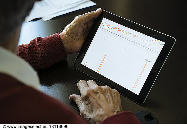 Cropped image of senior man examining graph on tablet computer in financial advisor's office