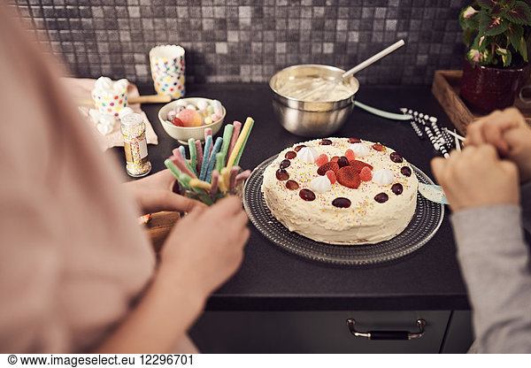 Cropped image of siblings standing by decorated cake at kitchen counter