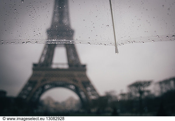 Cropped image of umbrella against Eiffel Tower during rainy season