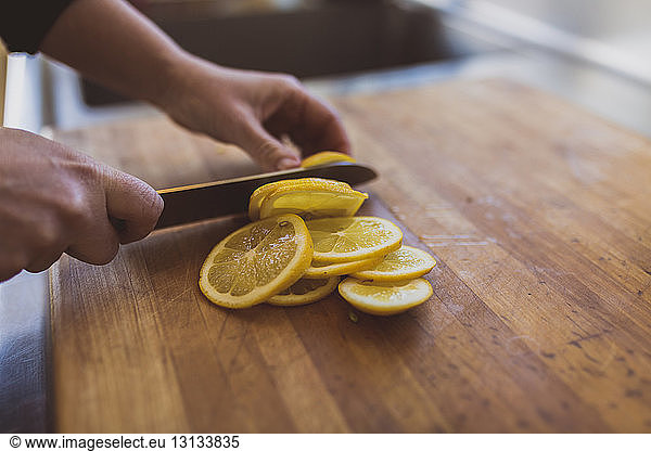 Cropped image of woman cutting lemon on cutting board