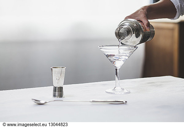 Cropped image of woman hand pouring alcohol in martini glass